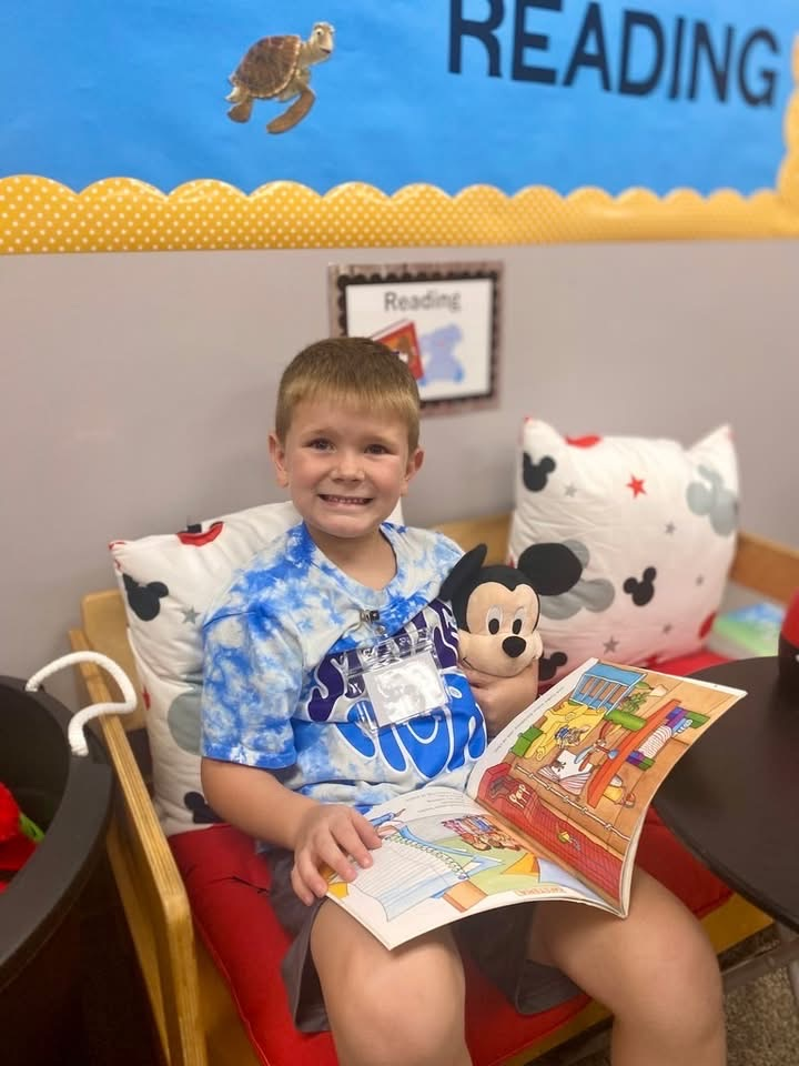 student reading book sitting on chair