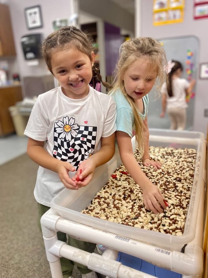 two students playing with beads in a box