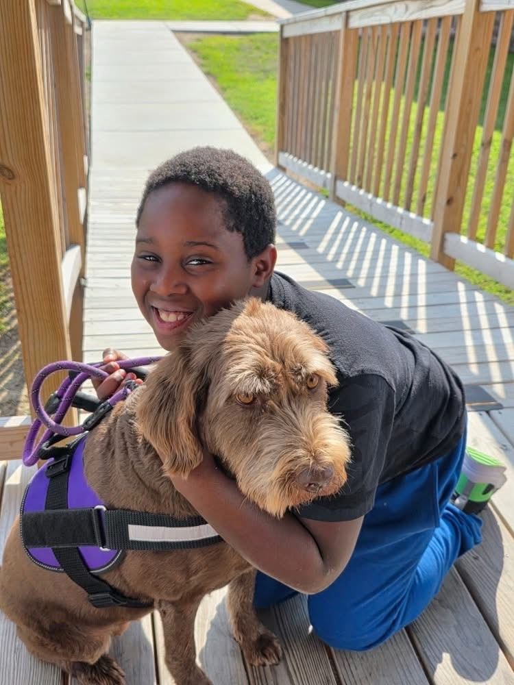 student hugging brown dog