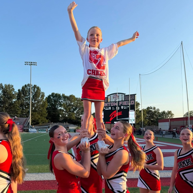 High school cheerleaders doing stunts with youth cheerleader