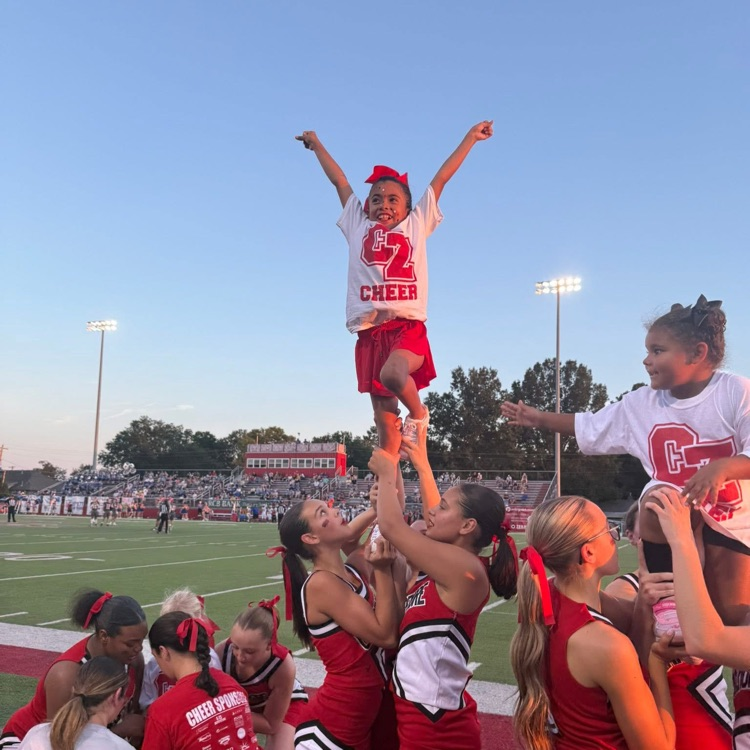 High school cheerleaders doing stunts with youth cheerleader