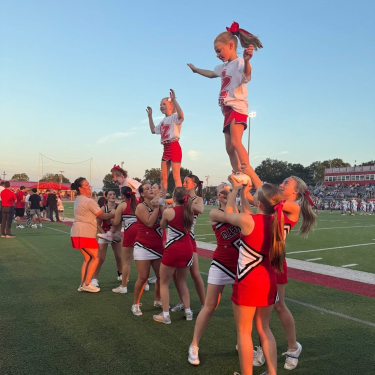 High school cheerleaders doing stunts with youth cheerleader