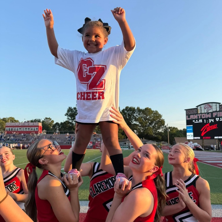 High school cheerleaders doing stunts with youth cheerleader