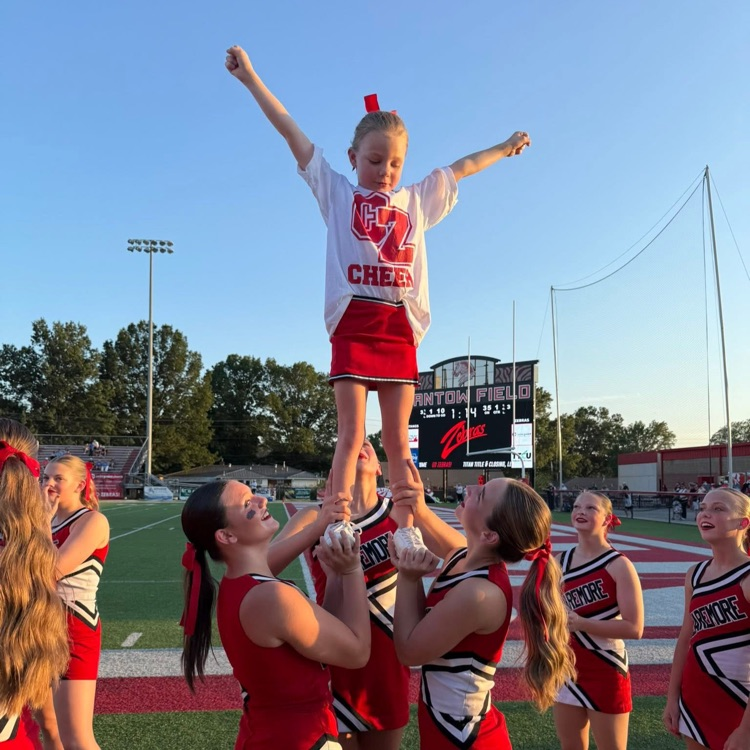 High school cheerleaders doing stunts with youth cheerleader