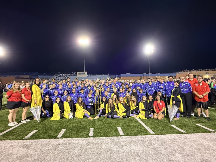 Band and uniforms on the field with trophy