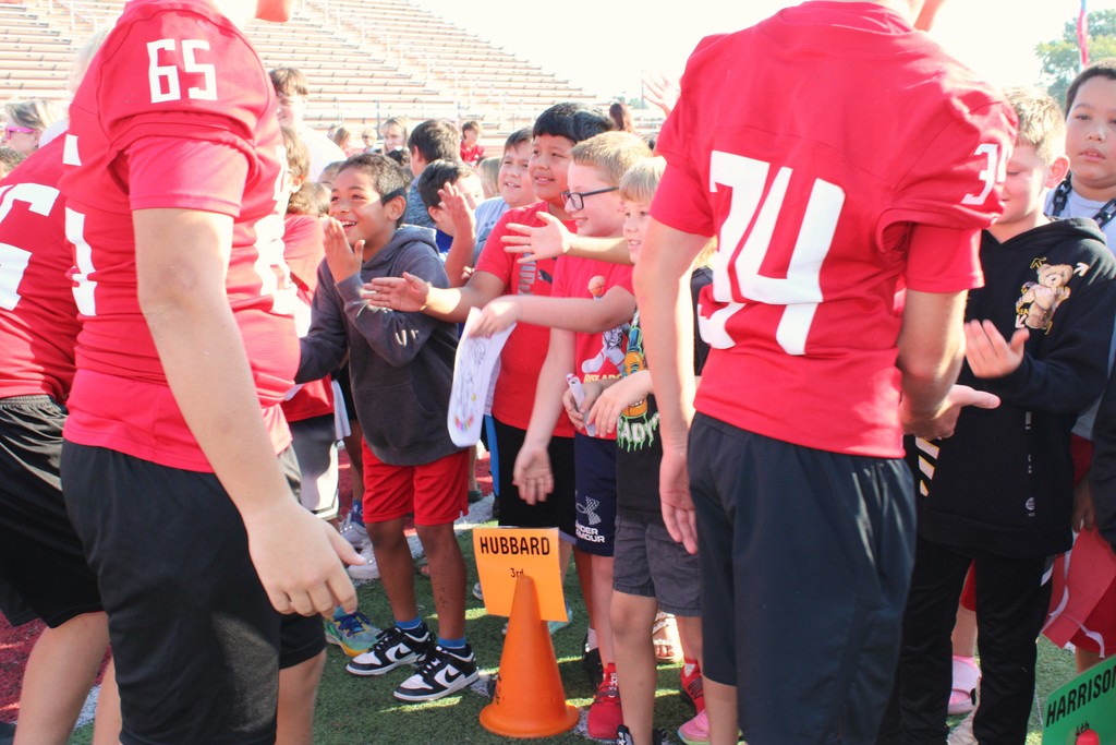 elementary students high fiving high school students