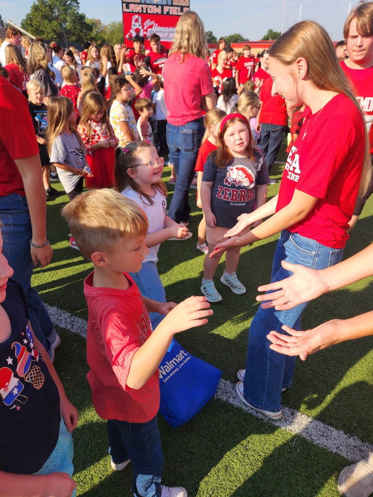 elementary students high fiving high school students
