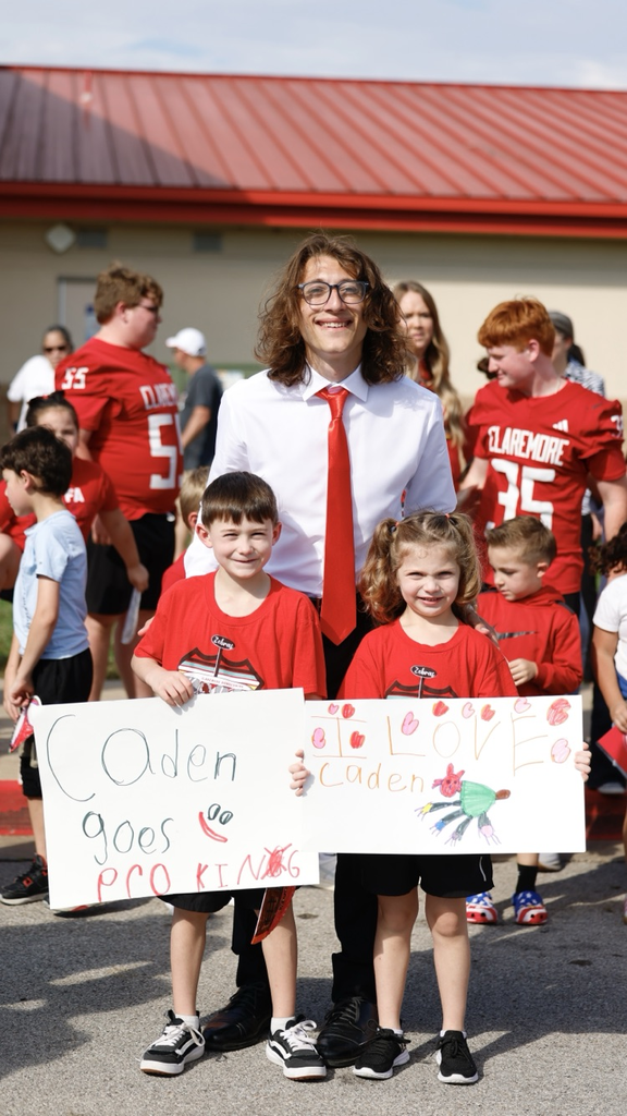 homecoming king with two kids holding signs