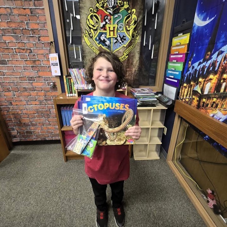 Student holding prize and book