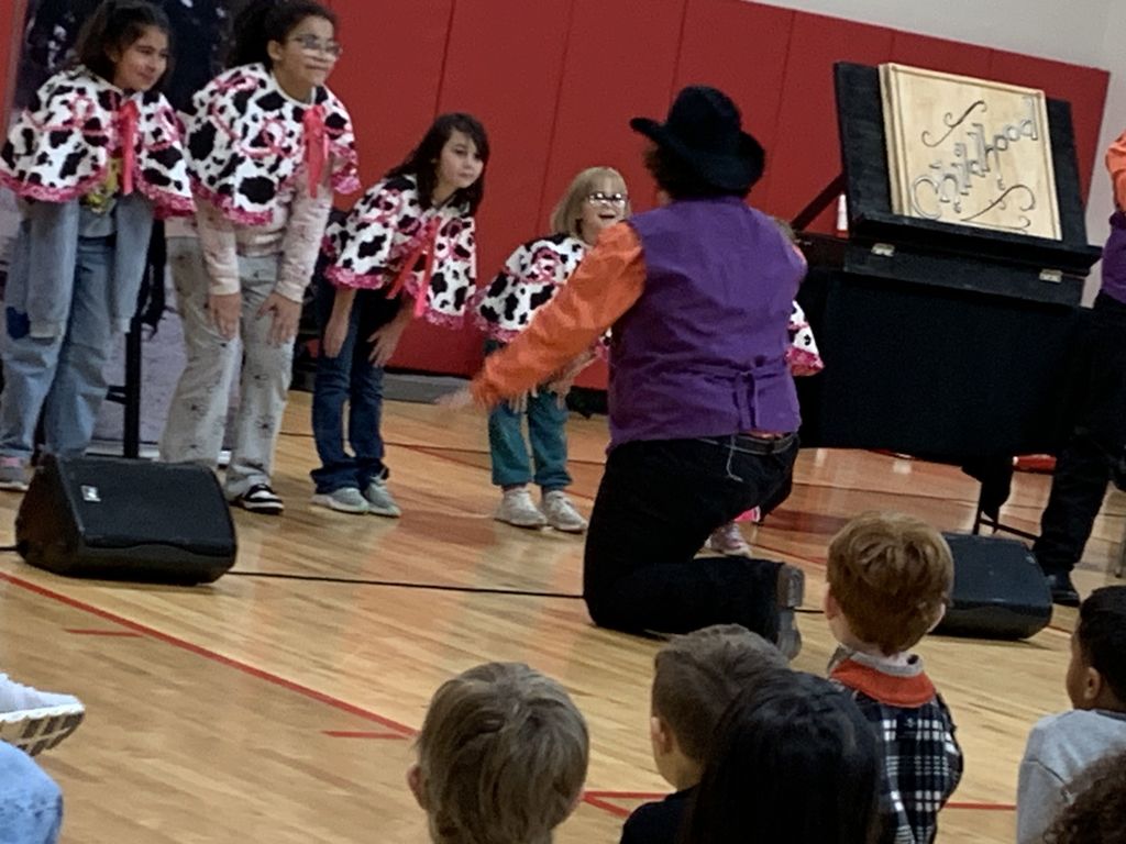 Students bent over as part of the motions to a song. 