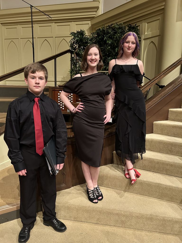 three Claremore students standing on a stair case smiling for a picture.