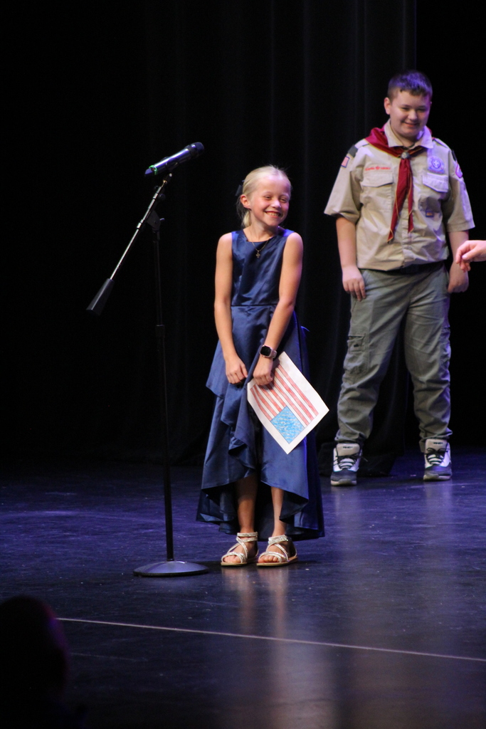 Student in blue dress smiling because the mic is too high for her to use.