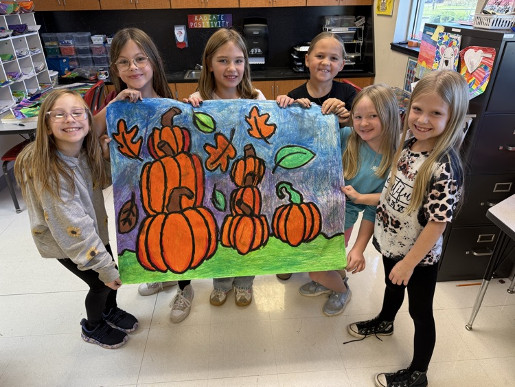Students smiling after they finished their art with pumpkins on it