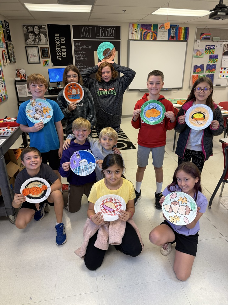 Students holding their decorated plates with fall scenes