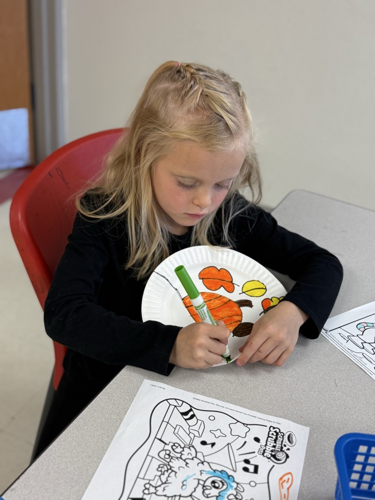Student drawing leaves in fall colors on a plate to hang on the wall