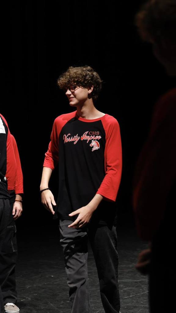 Students in black/red shirts "Improve" on stage 