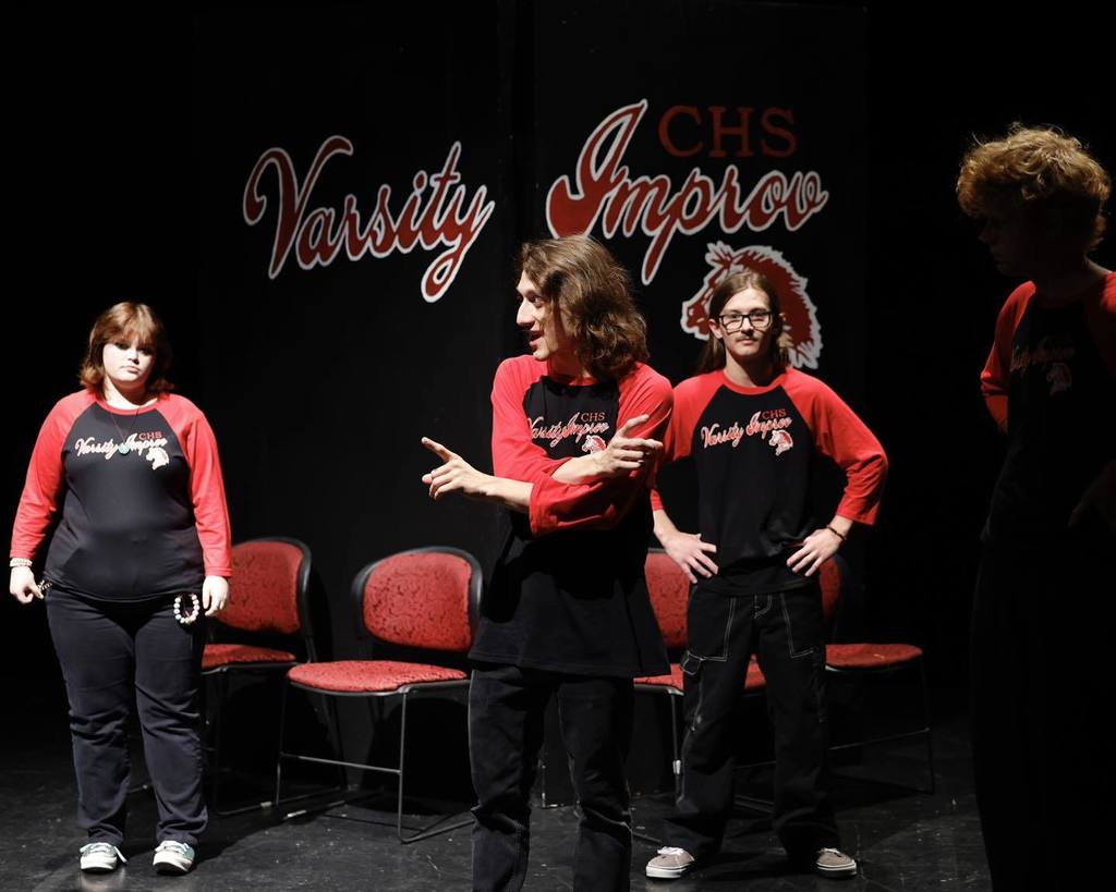 Students in black/red shirts "Improve" on stage 