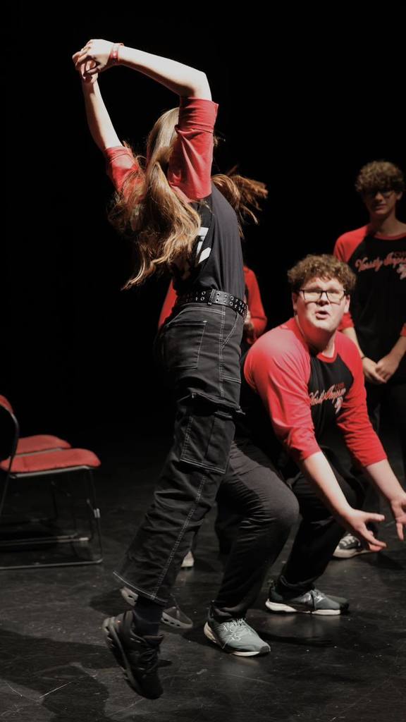 Student in black/red shirts "Improve" on stage dancing