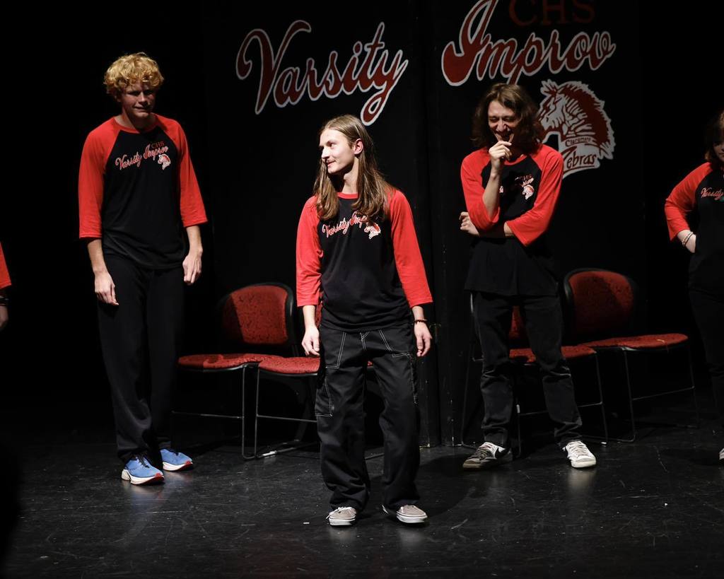 Students in black/red shirts "Improve" on stage 