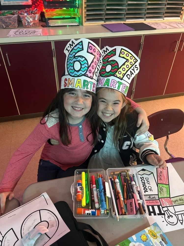 two students smiling with their 67 hats