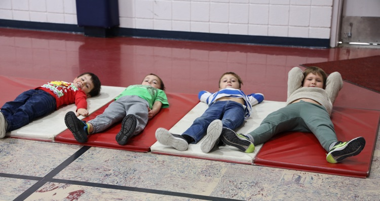 Four boys laying on a mat