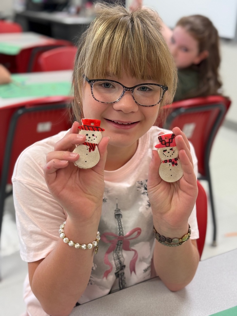 Student with glasses holding two snowmen nicely decorated.