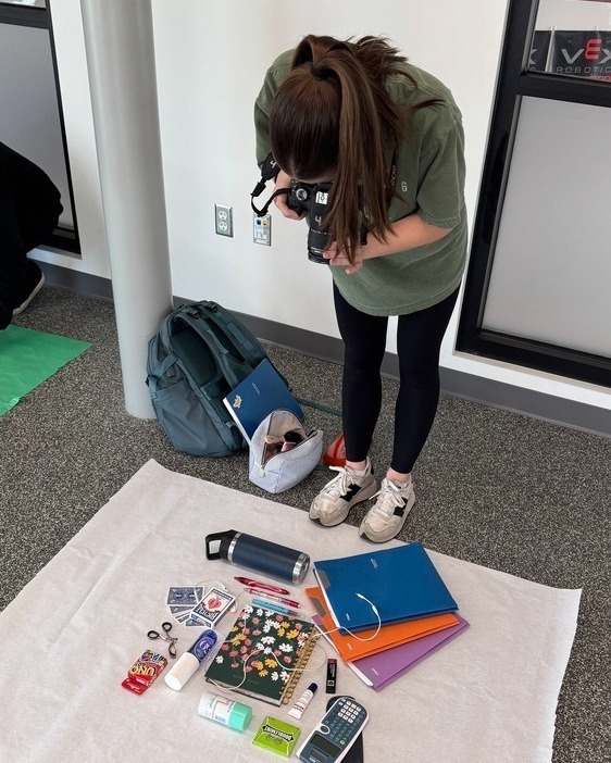 student taking photos of items on the floor