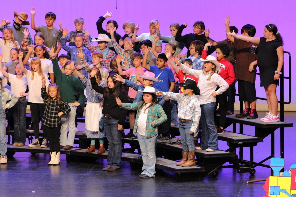 Students singing and pointing while wearing hats.