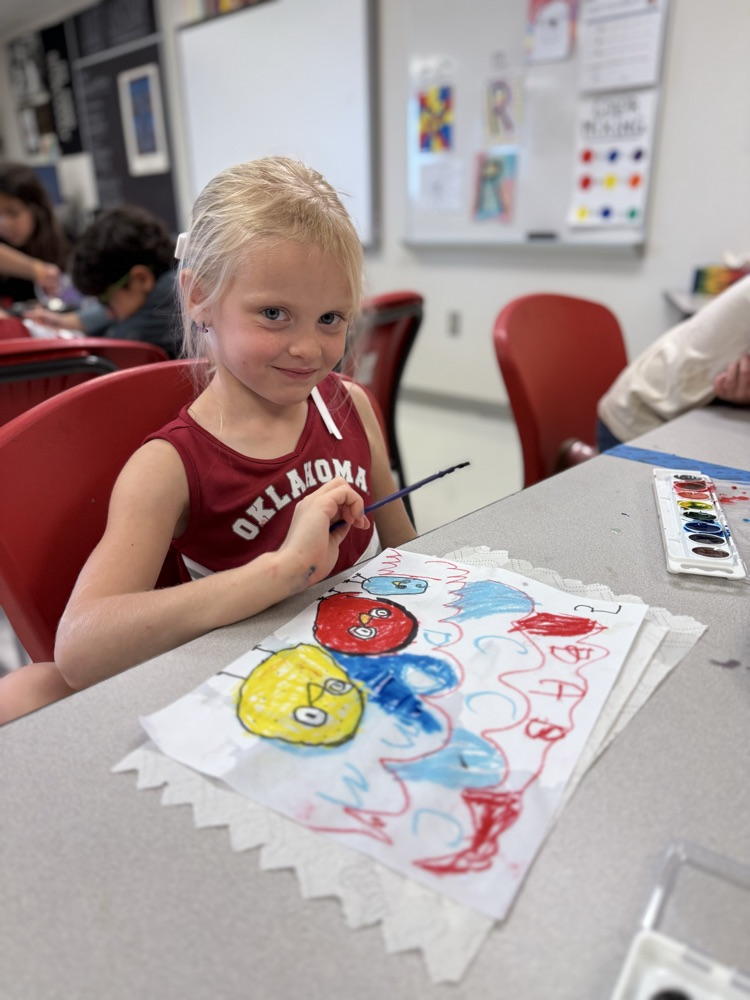 Student smiling while she paints in art