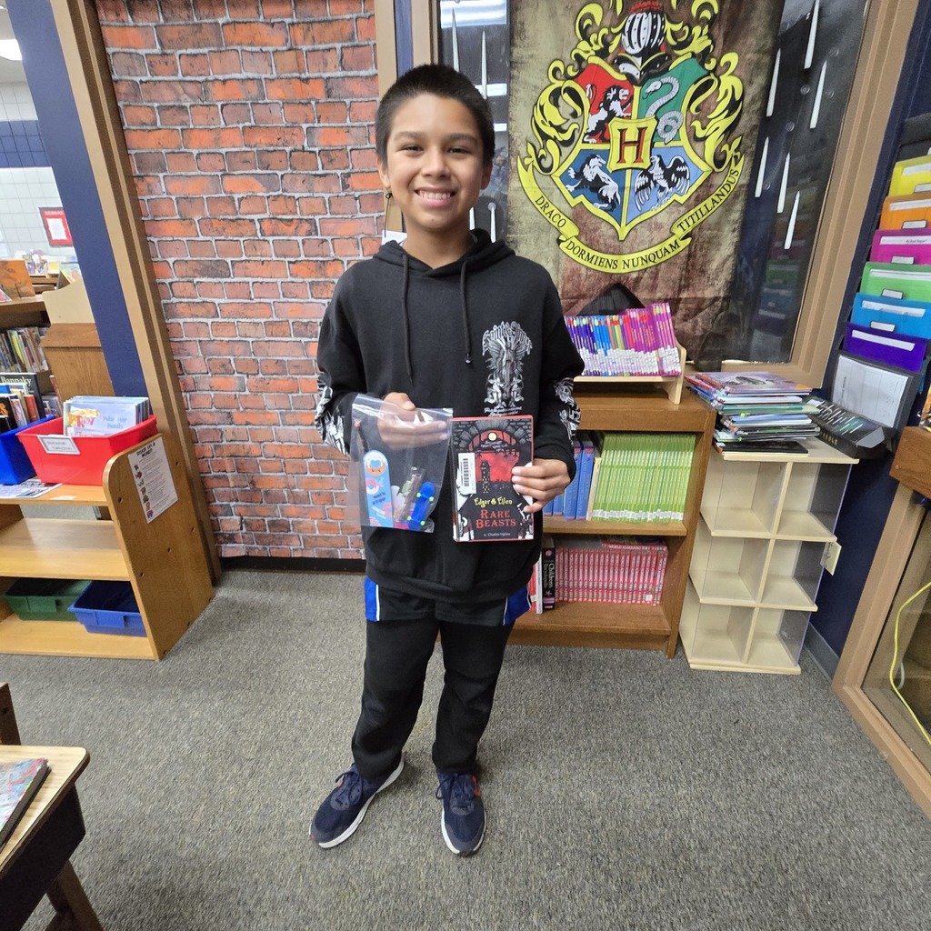 student holding book and prize while smiling