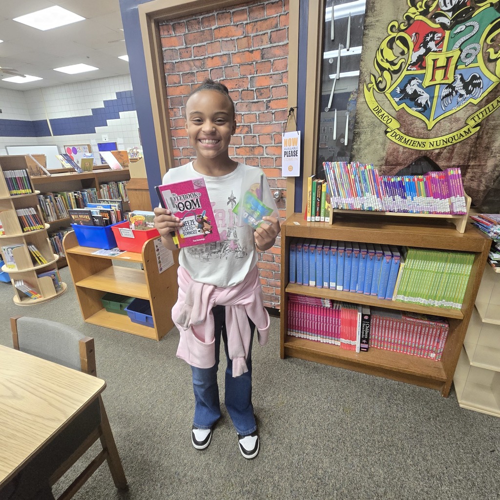 Student holding a book and a prize smiling