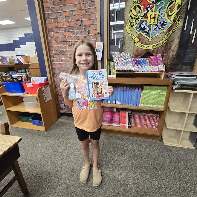 Student holding a book and a prize