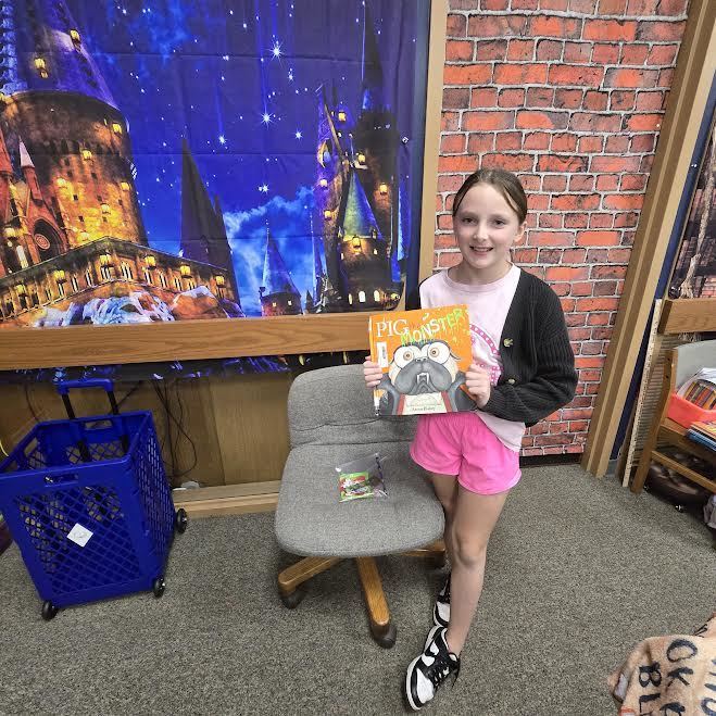 student holding book and prize