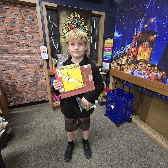 student holding book and prize