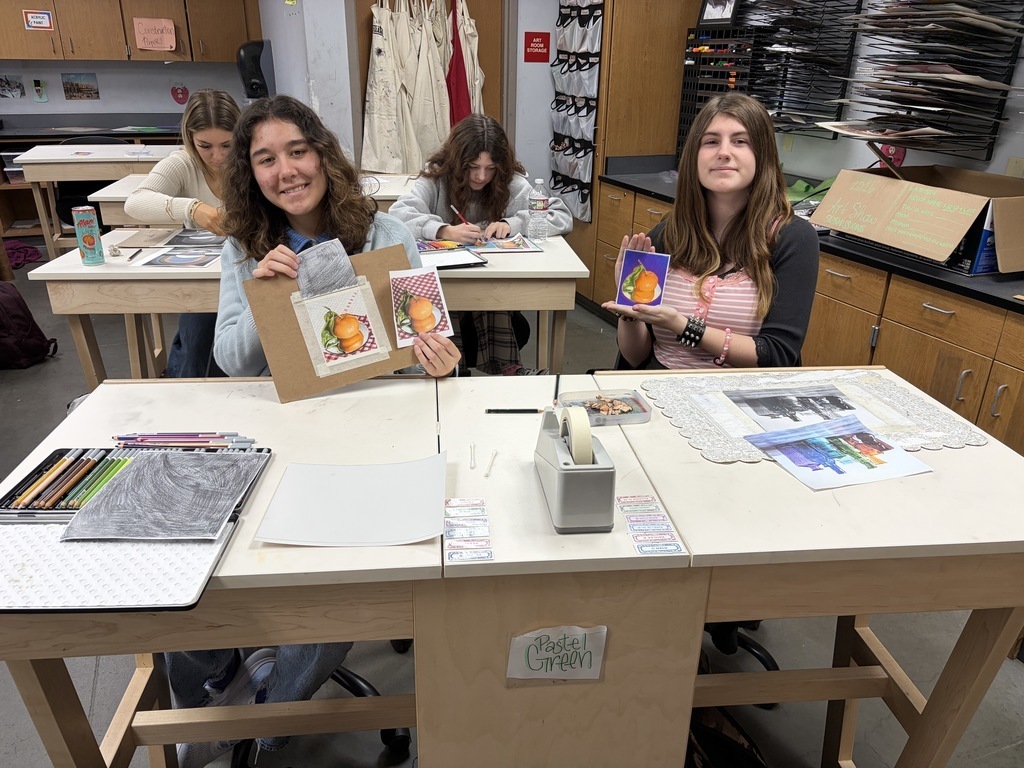 Students holding up their art work and smiling