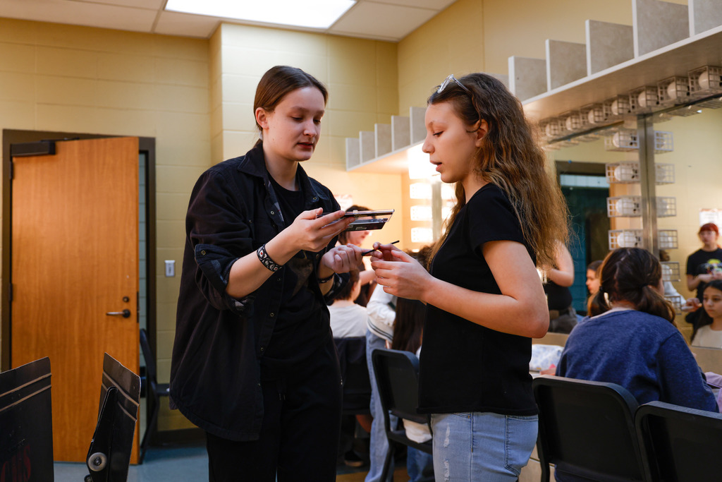 High school student helping Junior high student with make up.