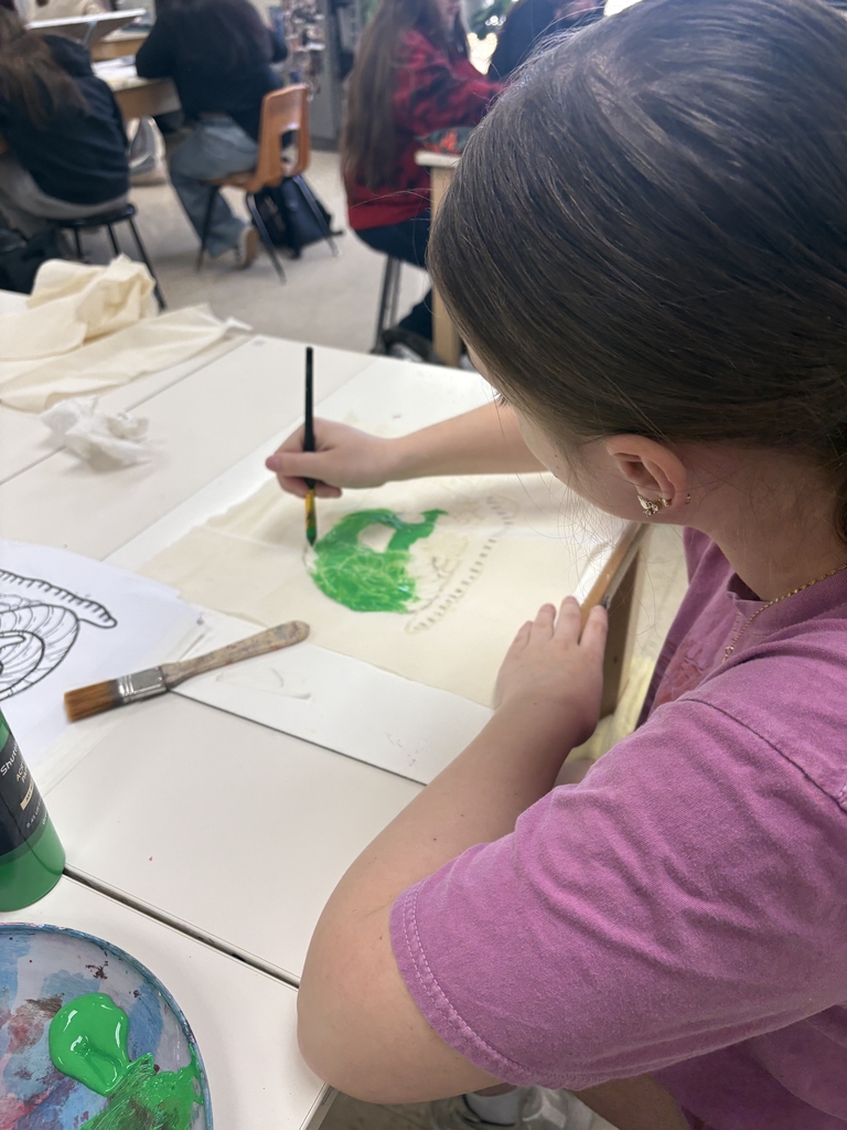 Student painting her art work green in studio art