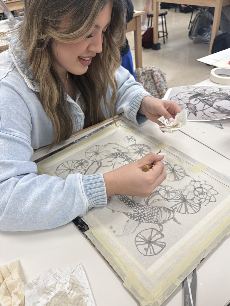 Students are discovering the exciting art of Batik! Batik is a fabric art technique where melted wax is applied to cloth to block out certain areas before dyeing. The wax is drawn on the fabric with a traditional tjanting tool, then the piece is hand painted. To reveal the final masterpiece, students remove the wax by ironing the fabric between sheets of newsprint and then washing away any remaining residue—unveiling bold contrasts, luminous color, and rich designs.