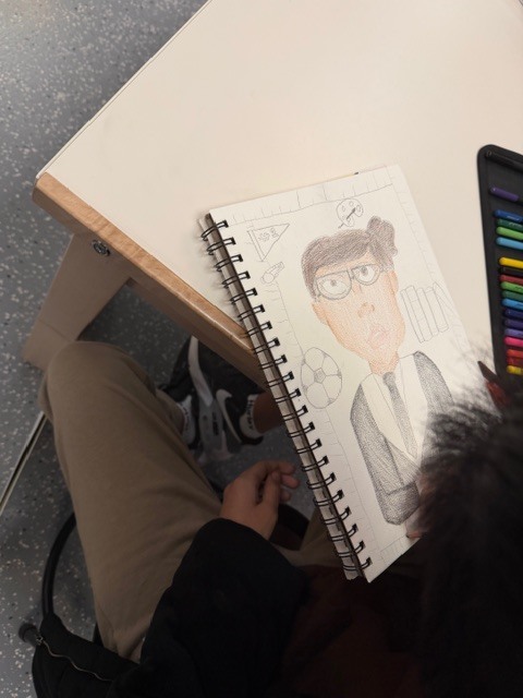 Student drawing a picture of another student in art using colored pencils 