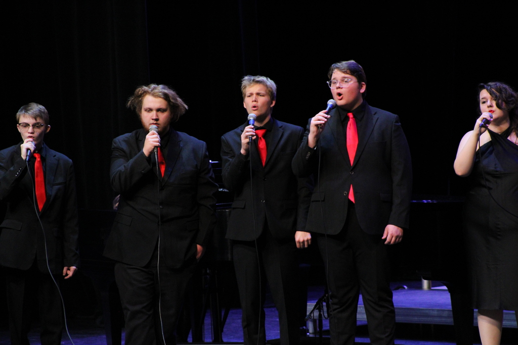 Room 701 on stage in dress black clothes and a red tie