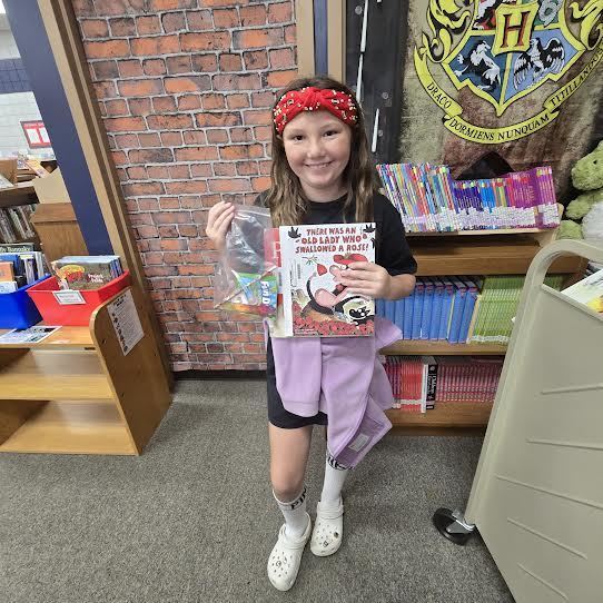 student holding a book and prize