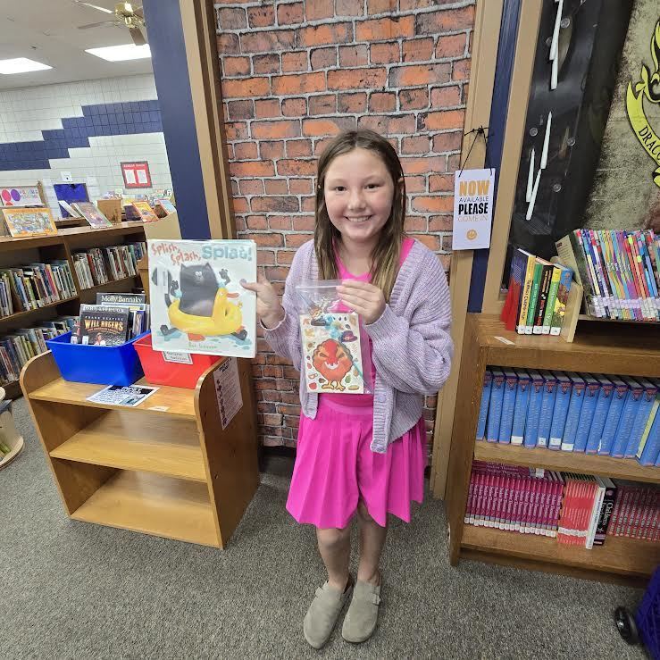 student holding book and prize