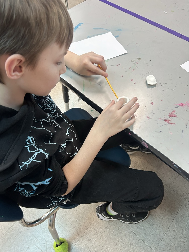 Student working on his clay project and painting it