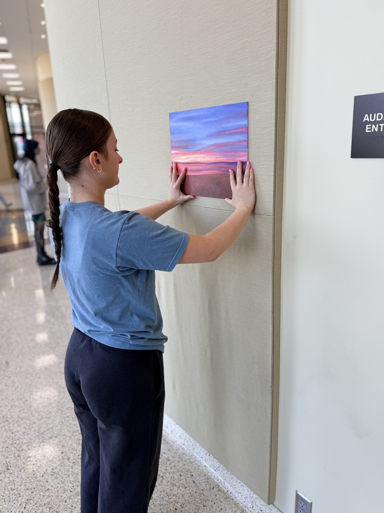 Claremore high school art students hanging up art in the P.A.C.