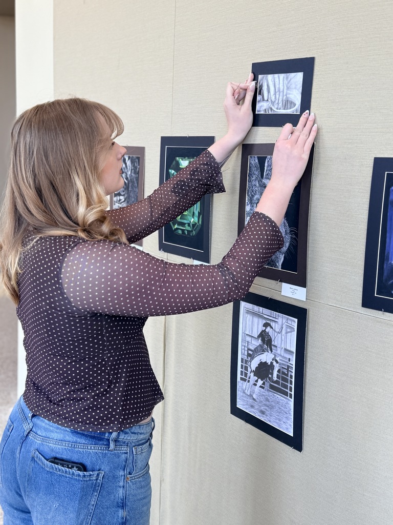 Claremore high school art students hanging up art in the P.A.C.
