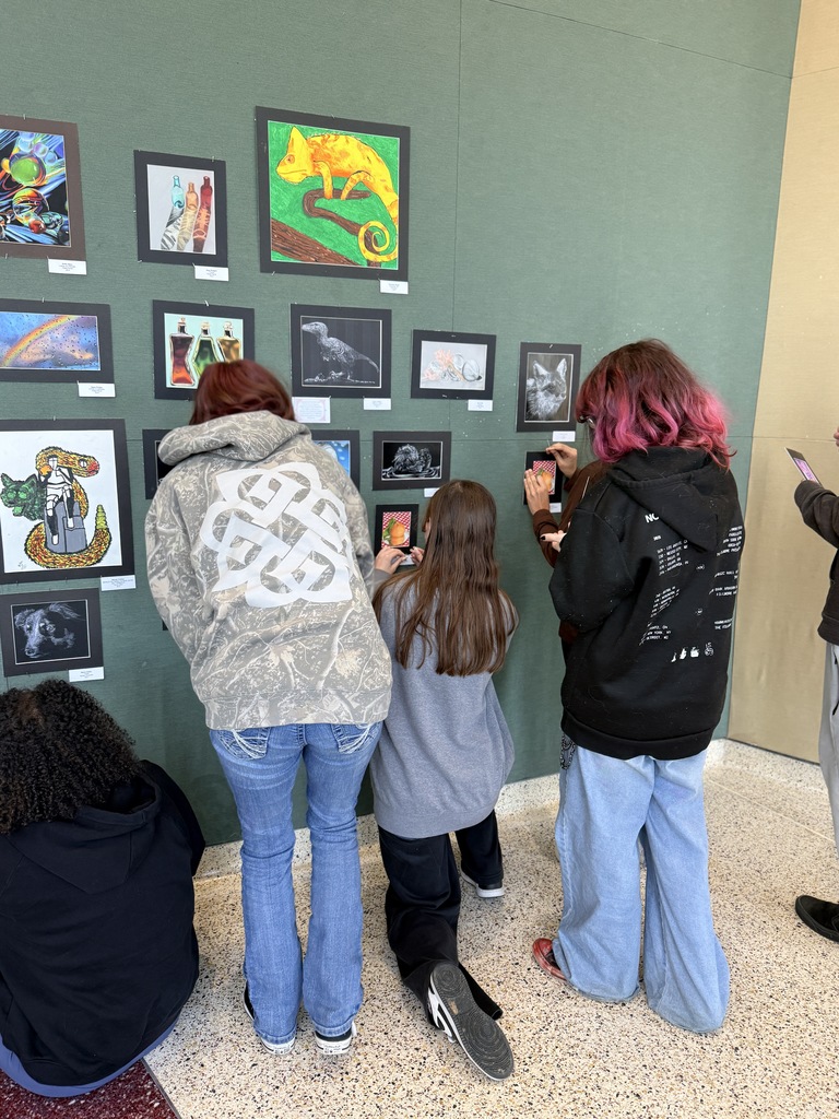 Claremore high school art students hanging up art in the P.A.C.