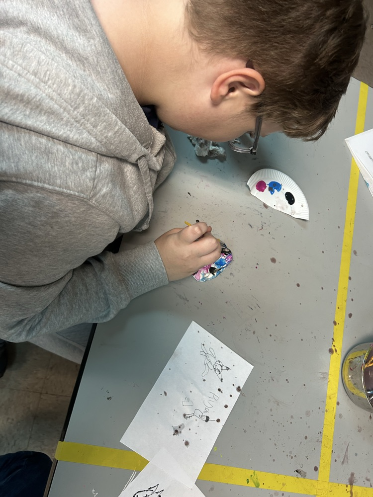 Student painting his clay creation in art class