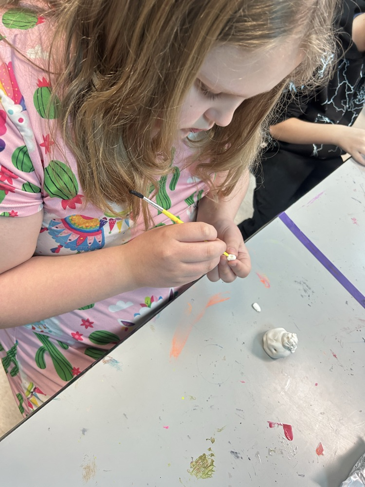 Student hand painting her clay creation