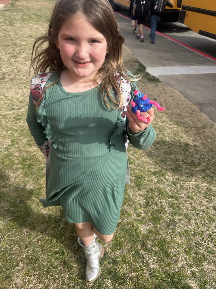 student holding clay creation she made in art