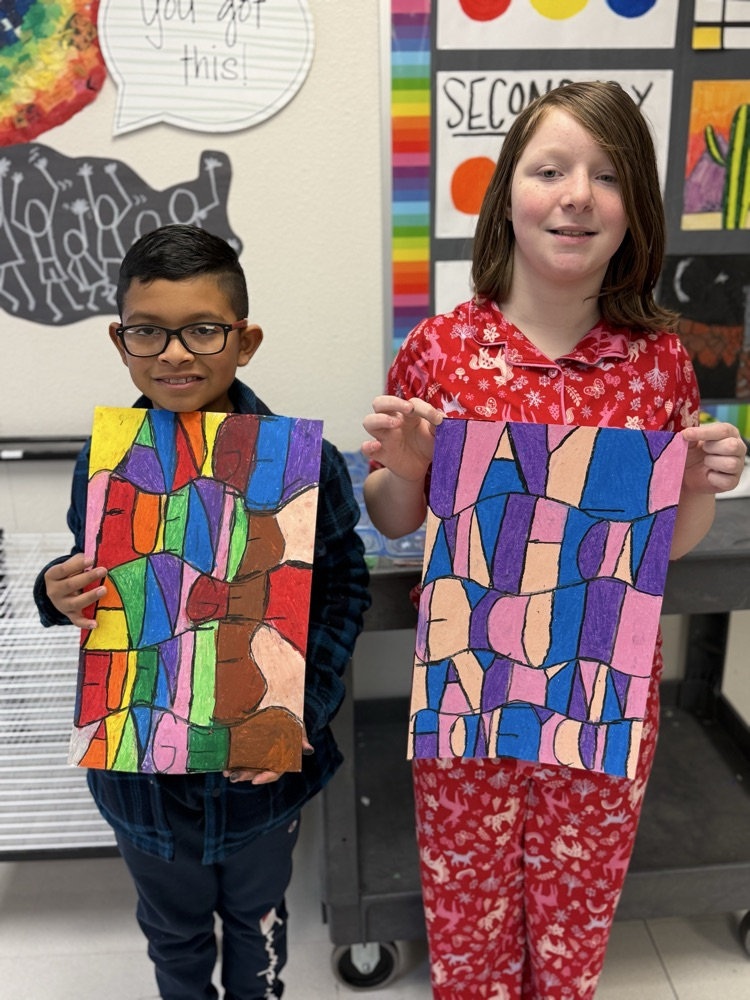 Students holding up their artwork they made in class.
